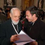 Father Seraphim Michalenko, MIC, left, and Br. Jason Lewis, MIC, discuss the text of the speech of Cardinal Francis Arinze during the morning session on Friday.