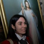 A Congress attendee poses for a picture beside the image of The Divine Mercy.